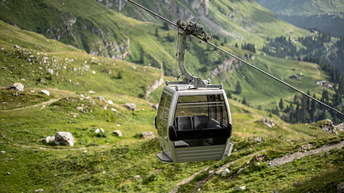 An illustrative alpine gondola cabin above green slopes